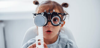 Little girl in eyewear in ophthalmology clinic have test of vision.