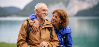 Senior couple hiking by lake in nature, resting.